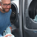 homme chargeant la machine à laver avec des serviettes bleues