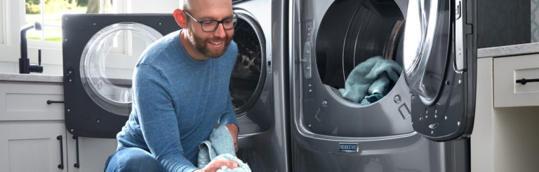 homme chargeant la machine à laver avec des serviettes bleues